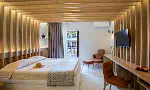 Et moderne hotelværelse med en dobbeltseng, træpaneler på væggene og udsigt til en altan. Værelset har et fjernsyn og en komfortabel siddeplads. (AI-genereret tekst)