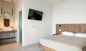 Hotelværelse med en dobbeltseng, vægmonteret TV og et åbent badeværelse. (AI-genereret tekst)