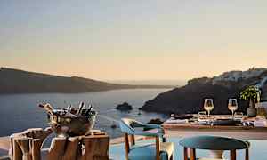 Et dækket bord med to siddepladser og en udsigt over havet og omkringliggende øer i solnedgang. (AI-genereret tekst)