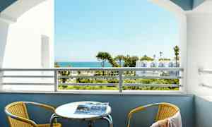 Udsigt fra en altan med havet i baggrunden. En gul stol og et bord er på altanen. (AI-genereret tekst)