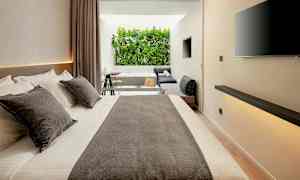 Moderne hotelværelse med stor seng, siddeområde og udsigt til grønne omgivelser. (AI-genereret tekst)