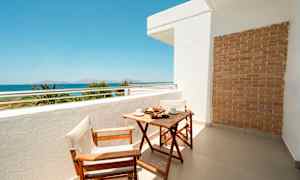 Altan med træbord og to stole, havudsigt i baggrunden. (AI-genereret tekst)