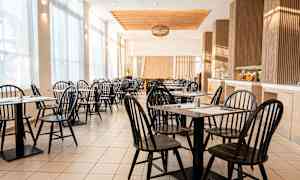 En lys og luftig café med sorte stole og borde. (AI-genereret tekst)