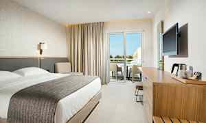 Moderne hotelværelse med dobbeltseng, siddeområde og møbleret altan. (AI-genereret tekst)