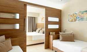 Et hotelværelse med opdelt design, med to senge og et træpanel der adskiller rummet. (AI-genereret tekst)