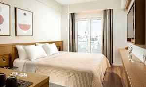 Hotelværelse med en dobbeltseng, dekoration på væggen og en glasdør, der fører ud til en balkon. (AI-genereret tekst)