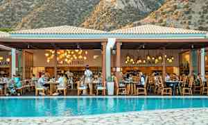 En restaurant ved en pool med bjerge i baggrunden. (AI-genereret tekst)