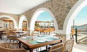 Udendørs serveringsområde med stenbuer og siddepladser med udsigt over havet. (AI-genereret tekst)