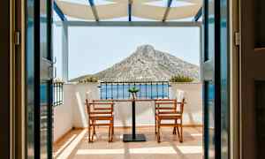 Udsigt fra en terrasse med to stole og et bord, mod et bjerg i baggrunden. (AI-genereret tekst)