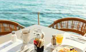 Morgenmad serveret ved bord med udsigt over vandet. (AI-genereret tekst)