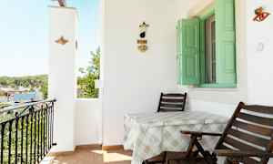 Altan med to stole og et bord, grønne skodder og vægdekoration. (AI-genereret tekst)