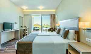 Billede af et hotelværelse med to enkeltsenge, moderne indretning og store vinduer som vender ud mod en terrasse. (AI-genereret tekst)