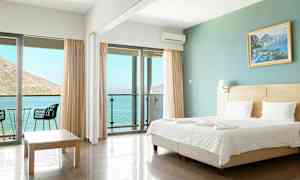 Et hotelværelse med en dobbeltseng, glasdøre som fører til en altan med havudsigt. (AI-genereret tekst)