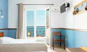 Hotelværelse med to senge, udsigt til en balkon og havet. (AI-genereret tekst)