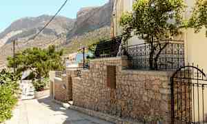 Stengærde med port og træer, bjerg i baggrunden. (AI-genereret tekst)