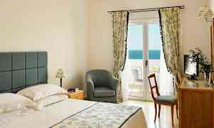 Et soveværelse med en dobbeltseng, en stol, et skrivebord og en balkon med havudsigt. (AI-genereret tekst)