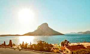 Solrig kyst med bjerg og hav i baggrunden. (AI-genereret tekst)