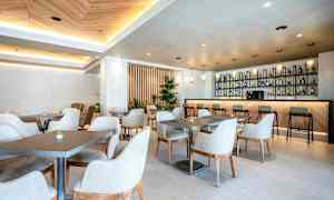 En moderne og lys café med borde og stole samt en veludstyret bardisk. (AI-genereret tekst)