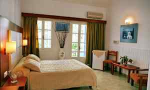 Hotelværelse med seng, bord og stole, vindue med gardiner. (AI-genereret tekst)