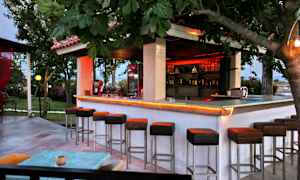 Udendørs bar med høje stole og træer omkring. (AI-genereret tekst)