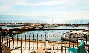 Udsigt fra en altan mod en havn med både og hav i baggrunden. (AI-genereret tekst)