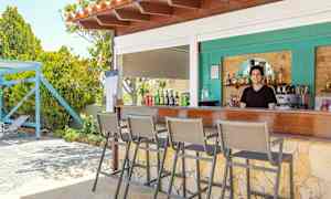 En udendørs bar med siddepladser og drikkevarer på disken. (AI-genereret tekst)