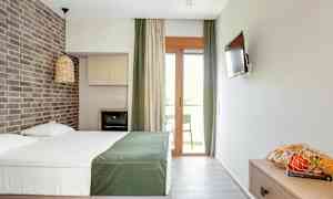 Et hotelværelse med en dobbeltseng, en murstensvæg, en TV, en altan og en kurv med frugt på et bord. (AI-genereret tekst)