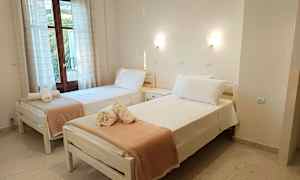 To enkeltsenge med redte lagner og håndklæder placeret ovenpå, stående i et rum med vindue og lyse vægge. (AI-genereret tekst)