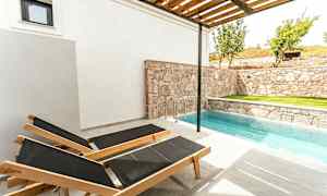 To liggestole ved en lille pool ved siden af en stenmur. (AI-genereret tekst)