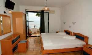 Et hotelværelse med to enkeltsenge og en altan med udsigt over havet. (AI-genereret tekst)