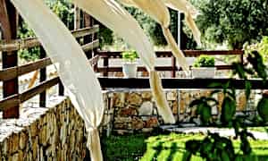 Dekorative tøjmønstre blæser i vinden på en terrasse med stenmur og blomster. (AI-genereret tekst)