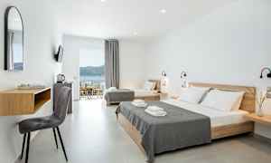 Moderne hotelværelse med lyse vægge, dobbeltseng og enkeltseng samt havudsigt. (AI-genereret tekst)