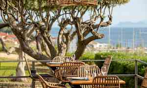 Udendørs servering med flettede stole og udsigt over havet. (AI-genereret tekst)