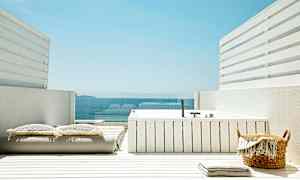 En hvid terrasse med et spabad, puder og udsigt over havet. (AI-genereret tekst)