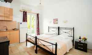 To enkeltsenge med lyserøde tæpper i et værelse med køkkenudstyr. (AI-genereret tekst)