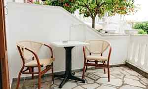 En lille terrasse med to stole og et bord foran et appelsintræ. (AI-genereret tekst)