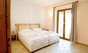 To senge med hvide lagner i et hotelværelse med døre, der fører ud til altanen. (AI-genereret tekst)