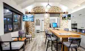 Et interiørbillede af et kontor med siddeområde, skrivebord og dekorativ stenmur. (AI-genereret tekst)