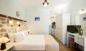 Hotelværelse med dobbeltseng, murstensvæg og lille køkkenområde. (AI-genereret tekst)