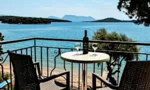 To stole og et bord med en vinflaske og glas på en altan med udsigt over havet. (AI-genereret tekst)