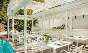 Udendørsmiljø med hvide borde og stole ved siden af en pool. (AI-genereret tekst)