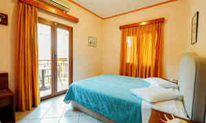 Et hotelværelse med en dobbeltseng, gardiner og en altandør. (AI-genereret tekst)