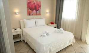 Et lyst og velordnet soveværelse med en dobbeltseng, hvide sengetøj og neutralt indretningsdesign. (AI-genereret tekst)