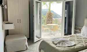 Hotelværelse med udsigt til en terrasse med bord, stole og en palme. (AI-genereret tekst)