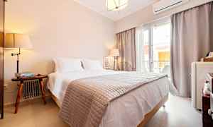 Et hotelværelse med en dobbeltseng, natbord og vindue der lader naturligt lys komme ind. (AI-genereret tekst)