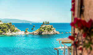 En lille ø med træer og et hus omgivet af blåt vand. (AI-genereret tekst)