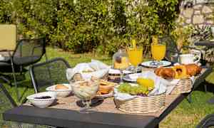 Havebord med morgenmad, der indeholder frugt, bagværk og drikke. (AI-genereret tekst)