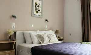 Et soveværelse med en seng, puder og et mørkelilla sengetæppe. (AI-genereret tekst)