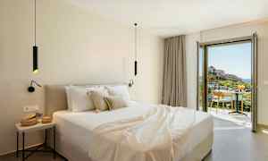 Moderne hotelværelse med dobbeltseng og altan, der tilbyder udsigt over et pittoresk landskab. (AI-genereret tekst)