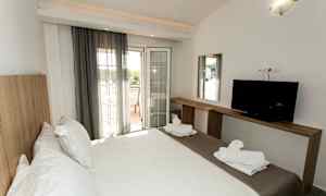 Et hotelværelse med en dobbeltseng, en TV på en træbænk og en altan med udsigt. (AI-genereret tekst)